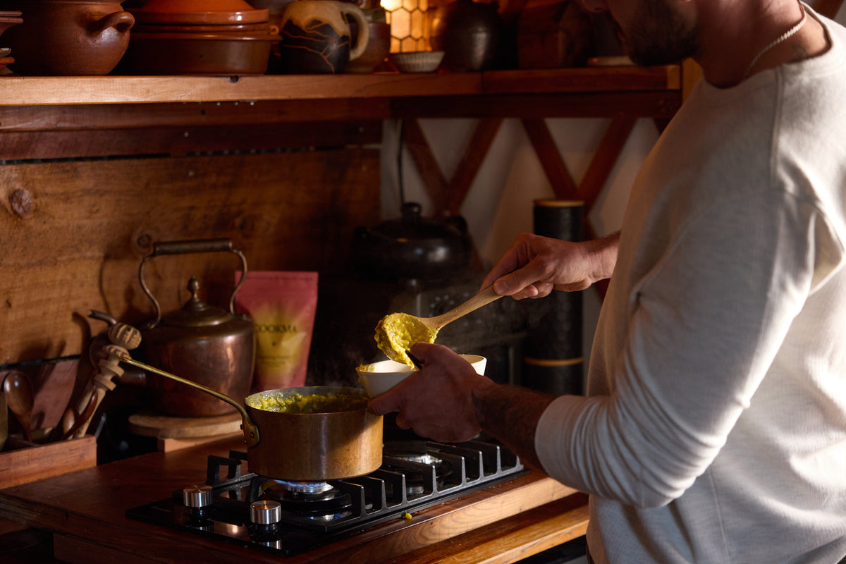 Hands stirring a pot of kitchari at a warm stove